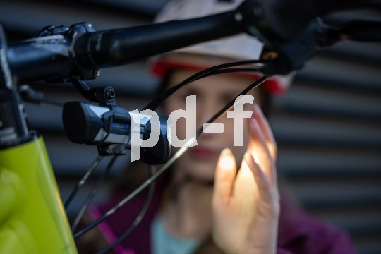 Eine Person hält die Hand in das Licht einer Fahrradlampe an einem Fahrradlenker.