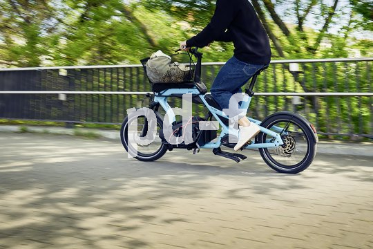 Mann fährt mit beladenem Cargobike durch die Stadt.