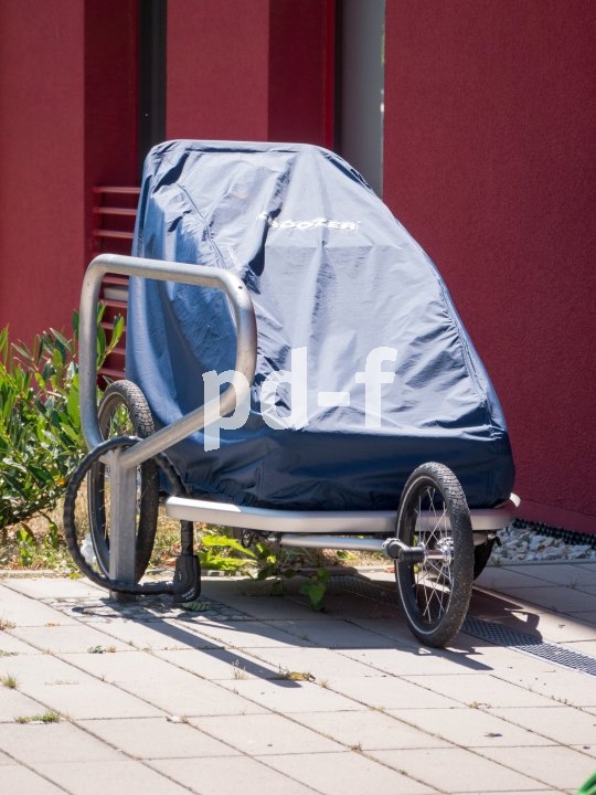 Eine passende Faltgarage schützt den Kinderanhänger vor Wind und Wetter.