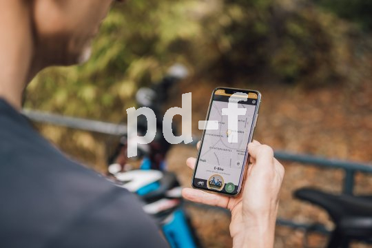 Die Bildunterschrift wird in Bälde eingefügt. Sie können uns aber gern auch per E-Mail oder Telefon kontaktieren, wir helfen gerne weiter. Blick über die Schulter einer Person, die ein Smartphone mit einer Karten-App vor sich hält.