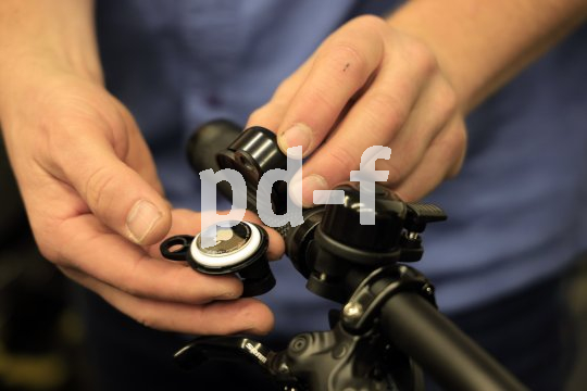Eine Person zeigt ein Apple Airtag im Inneren einer demontierten Fahrradklingel.
