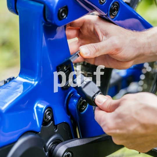 Eine Person schließt das Ladekabel an ein E-Bike an.