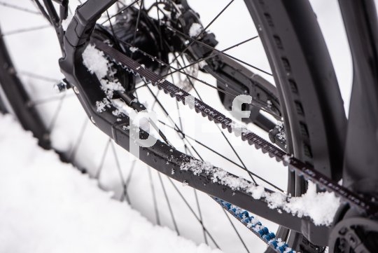 Der Riemenantrieb an einem Fahrrad im Schnee.