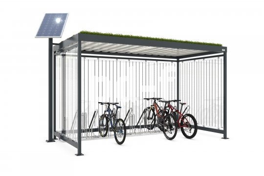 Ein überdachter Fahrradstellplatz mit Grünfläche auf dem Dach und einer Solarzelle daneben.