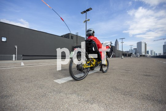 Eine Person fährt auf einem Liegerad in Richtung einer Großstadt-Skyline.