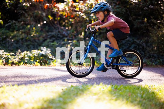 Ein Kind fährt ein blaues Fahrrad.