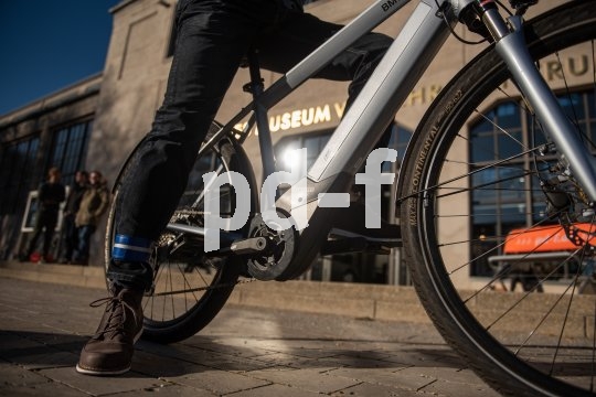 Blick auf den Motor eines E-Bikes auf dem eine Person sitzt.