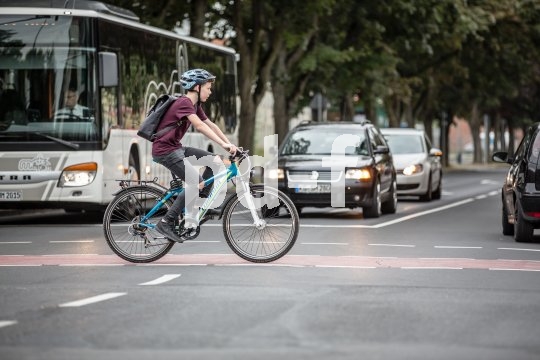 Ein Junge überquert auf einem Fahrrad eine Kreuzung.