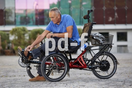 Diverse Um- und Anbaumöglichkeiten machen das Liegedreirad zum idealen Mobilisierer für Menschen mit Handicap. Ein Mann fixiert seine Schuhe auf dem Pedal eines Liegedreirads.