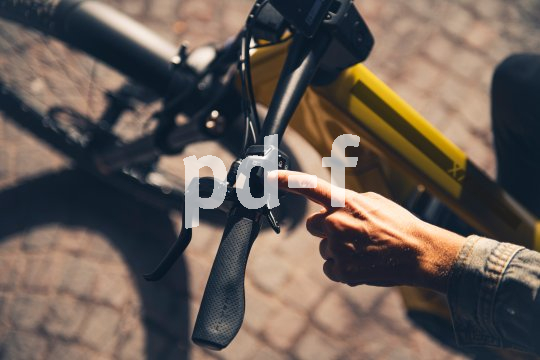 Hand zeigt auf Schalter am Lenker eines E-Bikes.