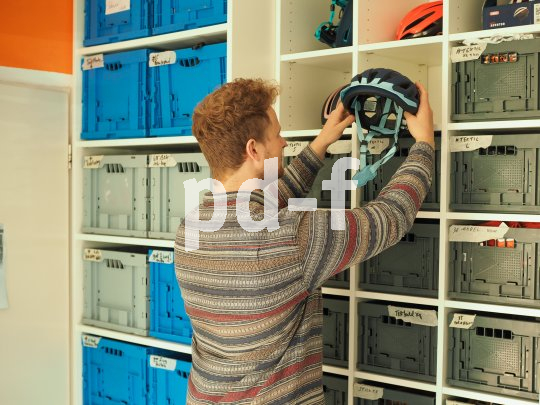 Ein Mann nimmt einen Fahrradhelm aus einem Regal.