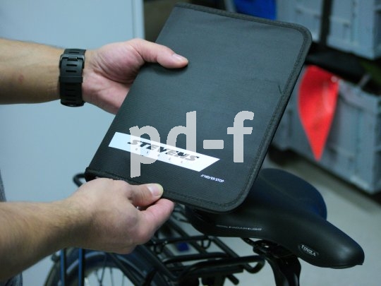 Eine Person hält eine Mappe mit dem Logo des Fahrradherstellers Stevens vor ein Fahrrad.