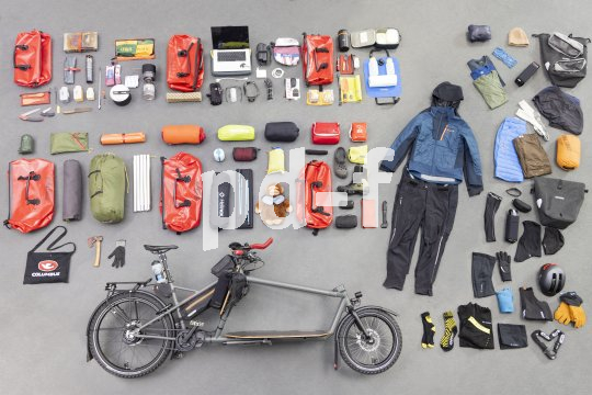 Auf dem Boden übersichtlich ausgebreitetes Gepäck und Ausrüstung sowie ein Lastenrad.