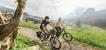 Zwei Personen auf E-Bikes in einer Gebirgslandschaft.