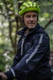 Ein Mann mit Fahrradhelm und teils nasser Regenjacke.
