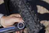 Eine Fahrradpumpe mit Manometer an einem Fahrradreifen. Der Zeiger der Skala steht zwischen zwei und drei Bar.