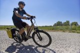Ein Radfahrer fährt mit einem E-Bike über einen Schotterweg auf dem Land.