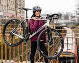 Frau trägt Fahrrad über Brücke