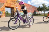 Ein Mädchen setzt an, mit dem Fahrrad loszufahren. Im Hintergrund fährt ein anderes Kind.