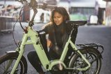 Eine Frau platziert den Akku eines E-Bikes im Rahmen.