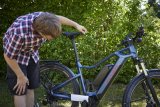 Ein Mann positioniert ein Schnurlot an der Spitze des Sattels an einem E-Bike.
