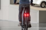 Am Gepäckträger eines Fahrrades leuchtet ein Bremslicht rot.