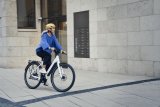 Frau fährt auf E-Bike durch eine Stadt.