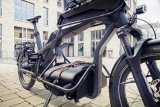 Cargobike mit Ladung parkt vor Gebäude.