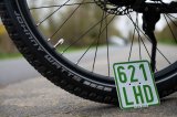 Nummernschild lehnt an Fahrradreifen.