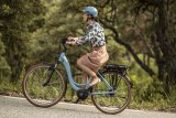 Eine Frau fährt auf einem E-Bike eine Straße bergan.