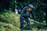 Frau fährt mit Mountainbike über Wiese.