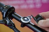 Ein Apple Airtag im Inneren einer demontierten Fahrradklingel an einem Lenker.
