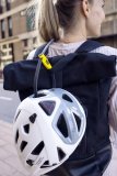 Ein weißer Fahrradhelm hängt am Rucksack einer Frau.