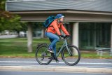 Eine Frau mit einem Rucksack fährt auf einem Fahrrad auf einem Radweg in der Stadt.