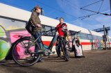 Zwei Männer stehen mit E-Bikes an einem Bahnsteig vor einem weiß-roten Fernverkehrszug.