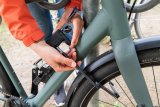 Detailansicht, wie eine Person ein Fahrrad anschließt.