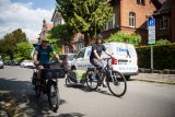 Ein Radfahrer auf einem Lastenrad und einer mit Anhänger fahren nebeneinander eine innerstädtische Straße entlang.