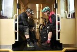 Ein Mann und eine Frau mit Fahrradhelmen sitzen sich im Zug gegenüber. Im Hintergrund ist ein Mountainbike zu erkennen.