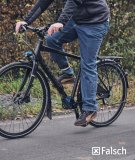 Eine Person fährt ein Fahrrad und streckt das linke Bein komplett durch, um treten zu können.