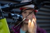 Eine Person hält die Hand in das Licht einer Fahrradlampe an einem Fahrradlenker.