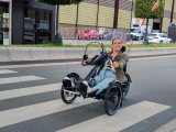 Die ehemalige Profifahrerin Kristina Vogel fährt mit einem Handbike auf einer Straße. Das Handbike hat vorne zwei Räder, hinten eins und wird mit Handkurbeln angetrieben.
