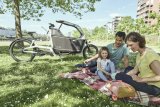 Eine Familie beim Picknick; im Hintergrund steht ein Lastenrad.