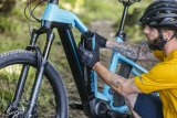 Ein Mann baut den integrierten Akku aus dem Rahmen eines E-Bikes aus.