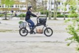 Mann fährt auf voll beladenem Cargobike durch die Stadt.