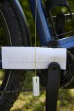 An der Kurbel eines E-Bikes ist ein Stück Papier mit einer aufgedruckten Skala platziert. Davor hängt ein Schnurlot.