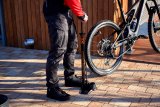 Eine Person pumpt mit einer Standpumpe den Hinterreifen eines E-Mountainbikes auf.
