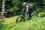 Eine Frau fährt auf einem Mountainbike einen Wiesenweg bergab.
