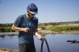 Ein Radfahrer pumpt mit einer kleinen Luftpumpe Luft einen Fahrradschlauch.