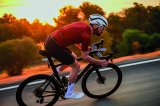 Ein Mann fährt auf einem Rennrad vor der tief stehenden Sonne eine Straße entlang.
