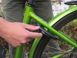 Eine Person hantiert am Schlüssel eines Rahmenschlosses an einem grünen Fahrrad.